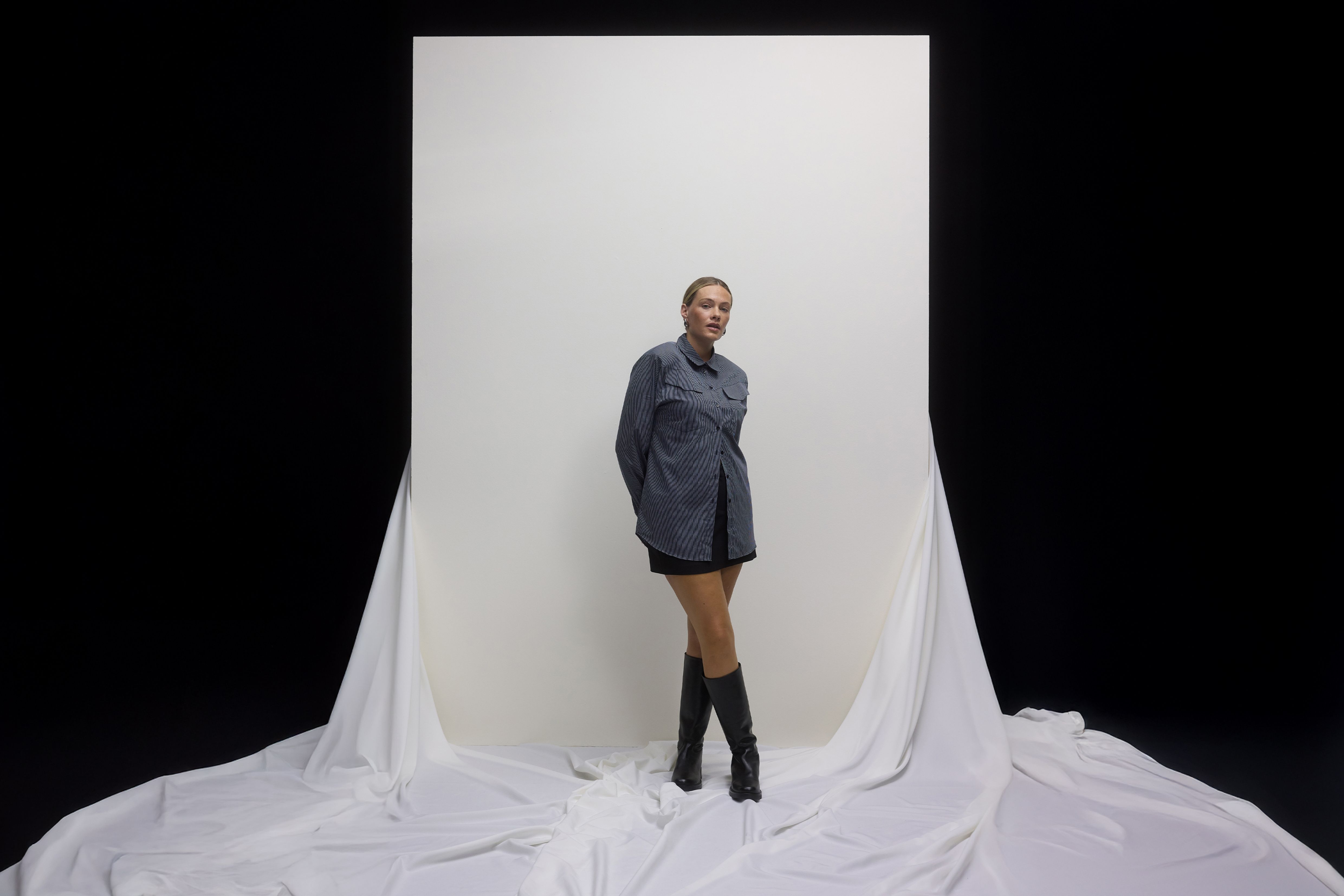 Mulher a usar uma camisa às riscas com uma mini-saia e botas.